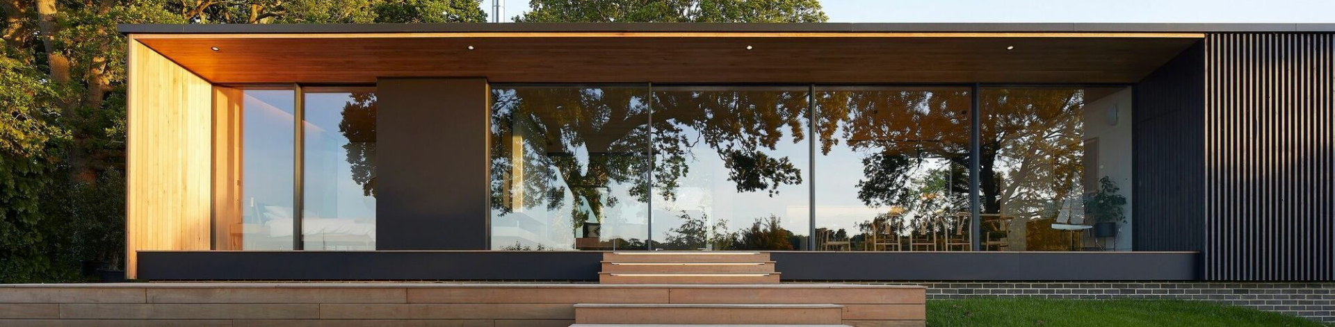 A modern house with large glass windows, wooden facade and a covered terrace