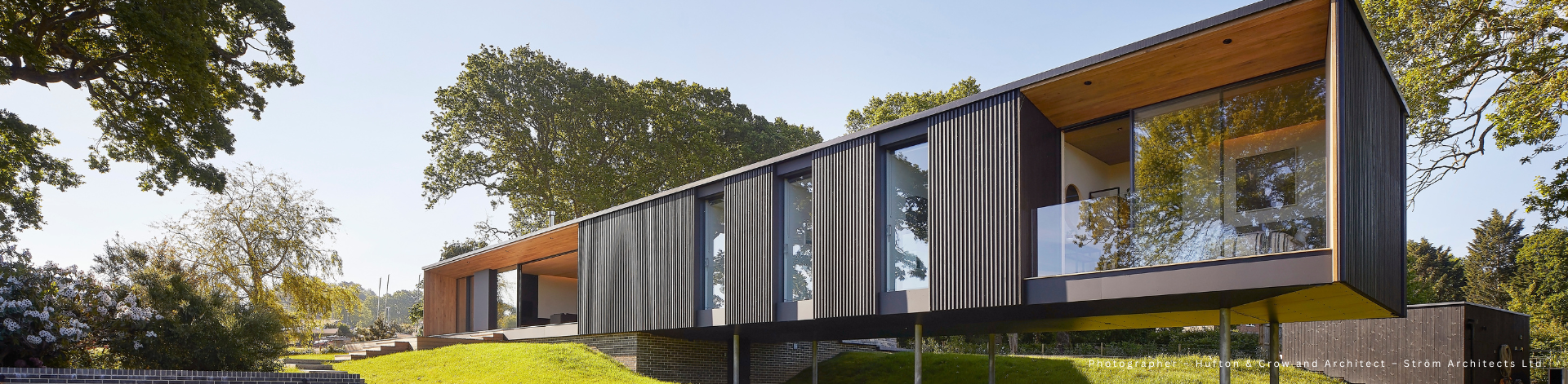 A modern house with large glass windows, wooden facade and a covered terrace